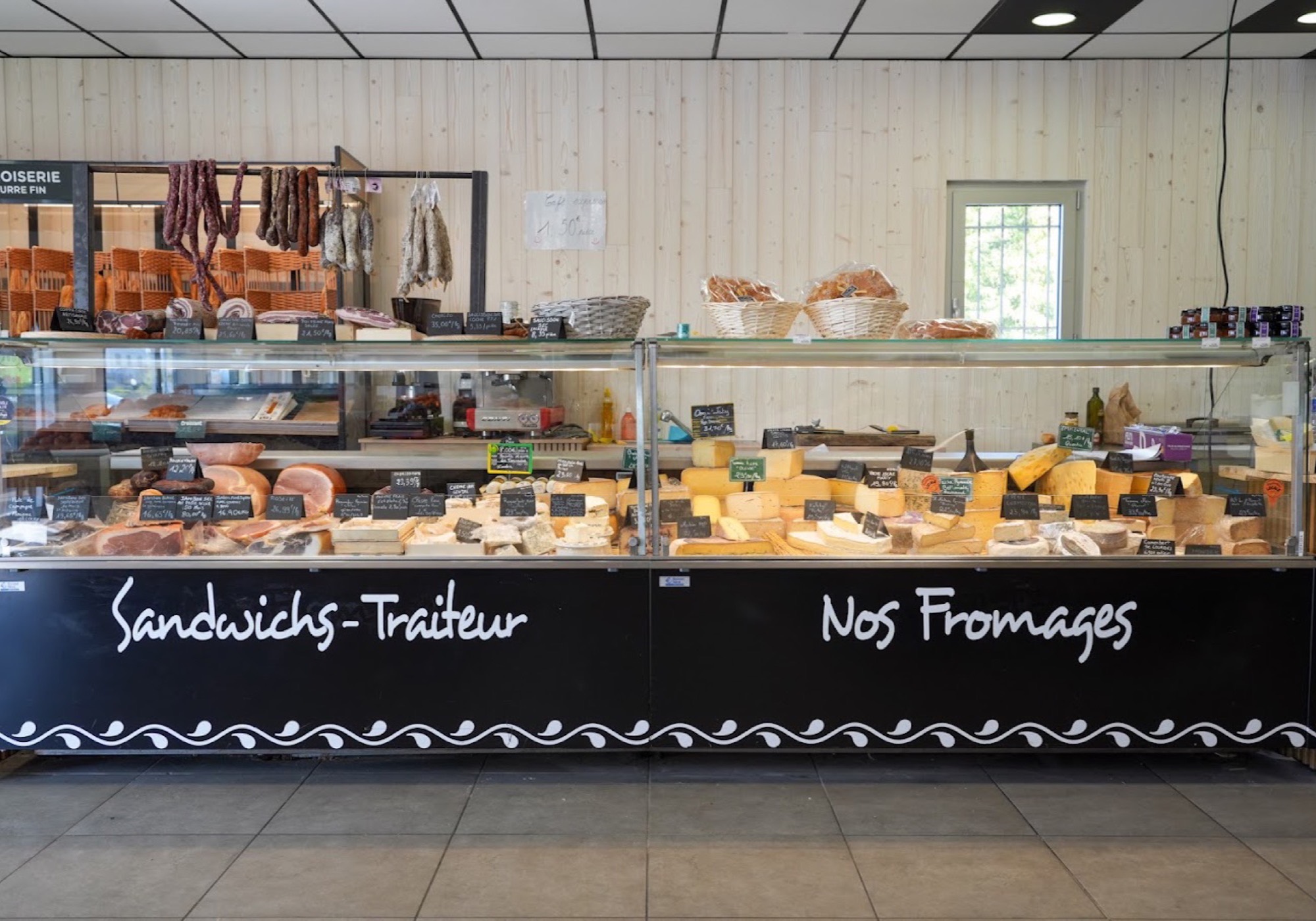 Le comptoir traiteur, les paniers de pain et la vitrine de charcuterie